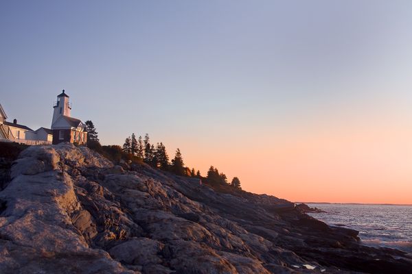 Pemaquid Point Lighthouse above the rocky Maine coast as the sky turns orange at sunset