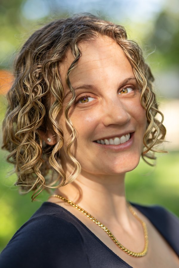 Meredith glancing up mid-smile, evening light in her curls
