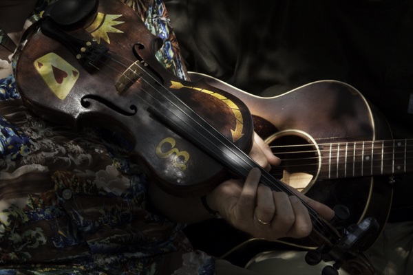 A hand-painted fiddle and an acoustic guitar in the hands of two American folk musicians